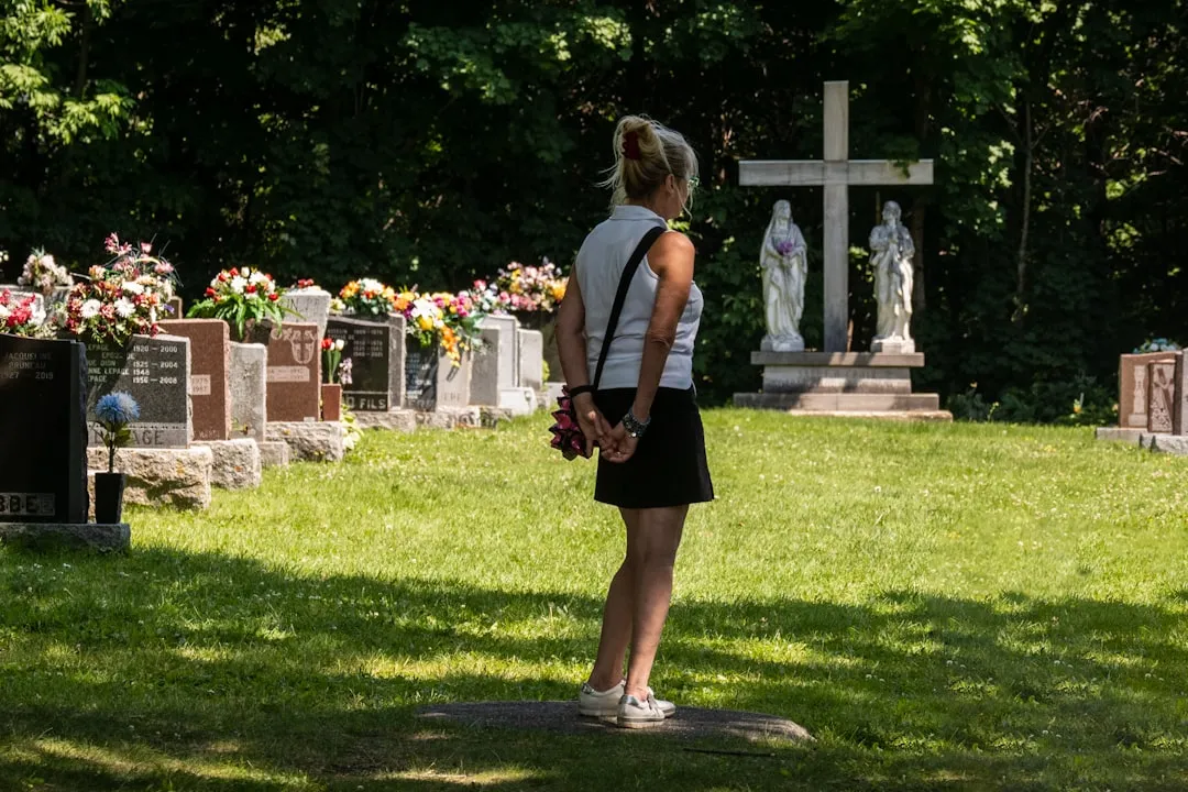 Woman visiting a memorial in a green cemetery during springtime