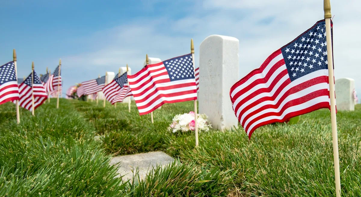 Rows of headstones at a national cemetery with American flags