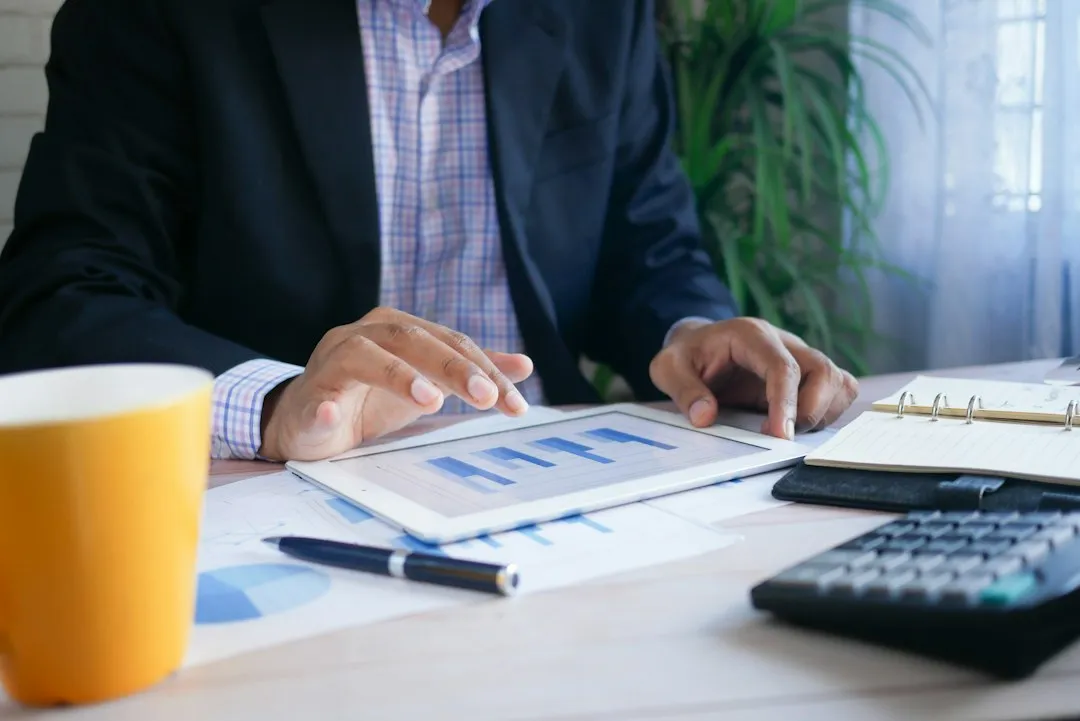 Professional analyzing market data and financial charts at an office desk