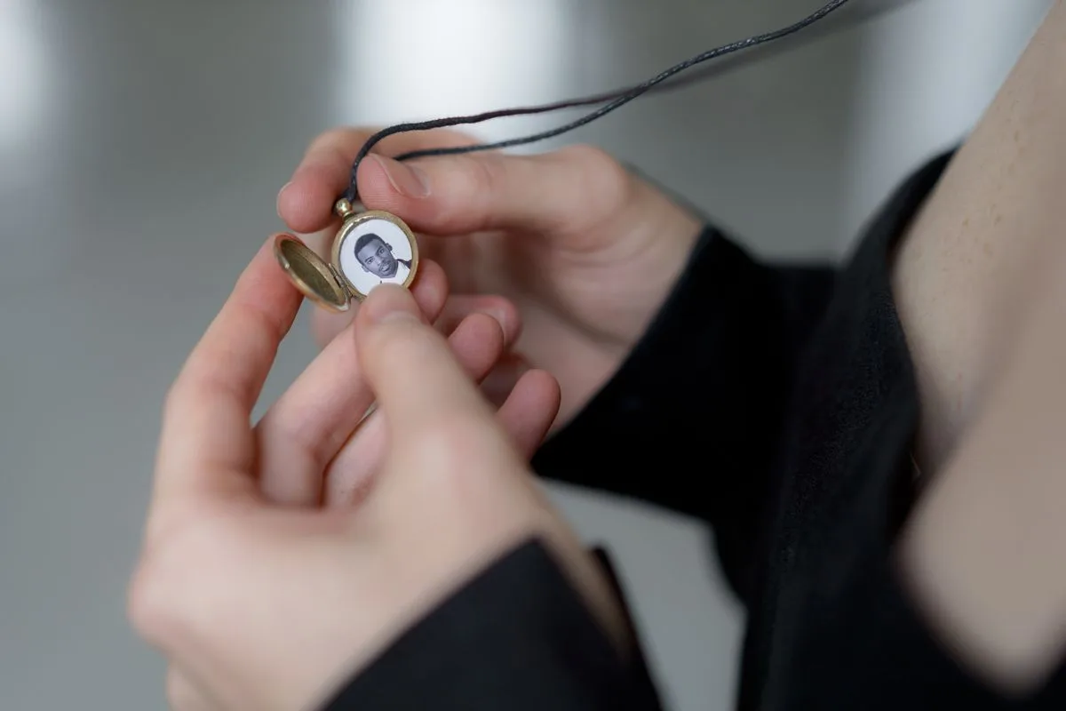 Close-up of hands holding a memorial keepsake locket pendant